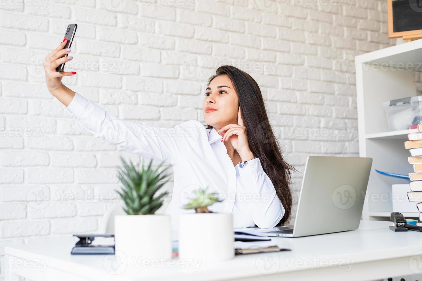 jonge latijnse vrouw in wit overhemd die selfie maakt foto