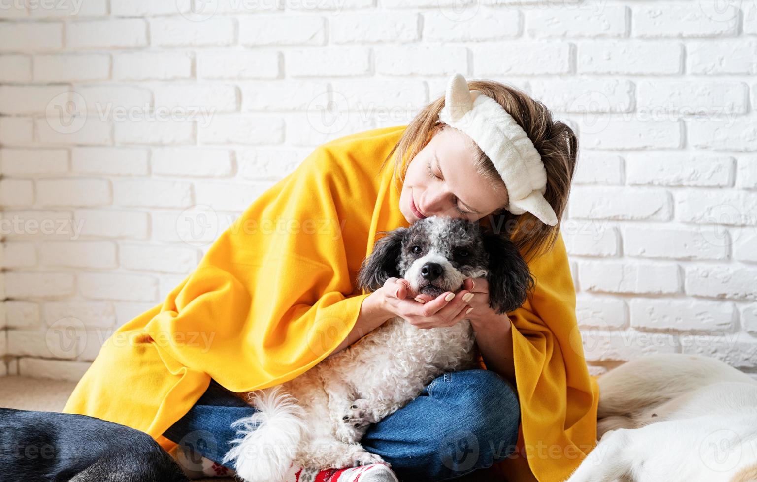 grappige jonge vrouw in gele plaid zittend met haar honden die een boek lezen foto