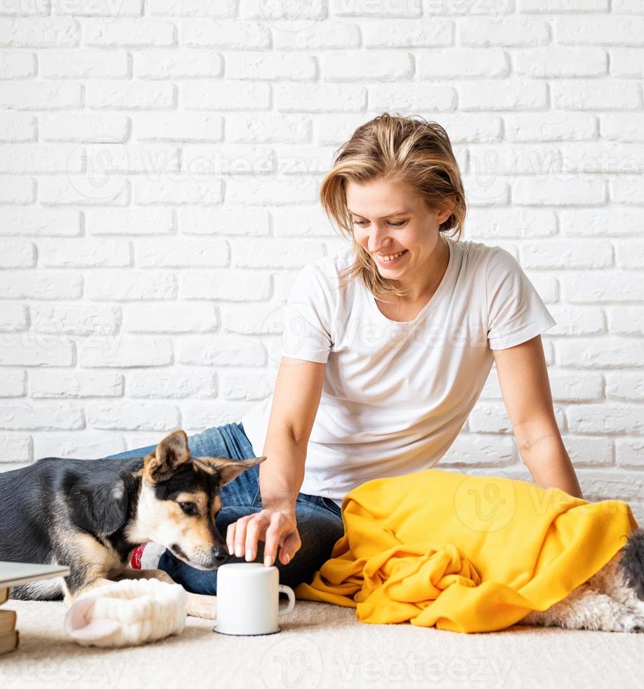 vrouw in gele plaid zittend op de vloer spelen met haar honden foto