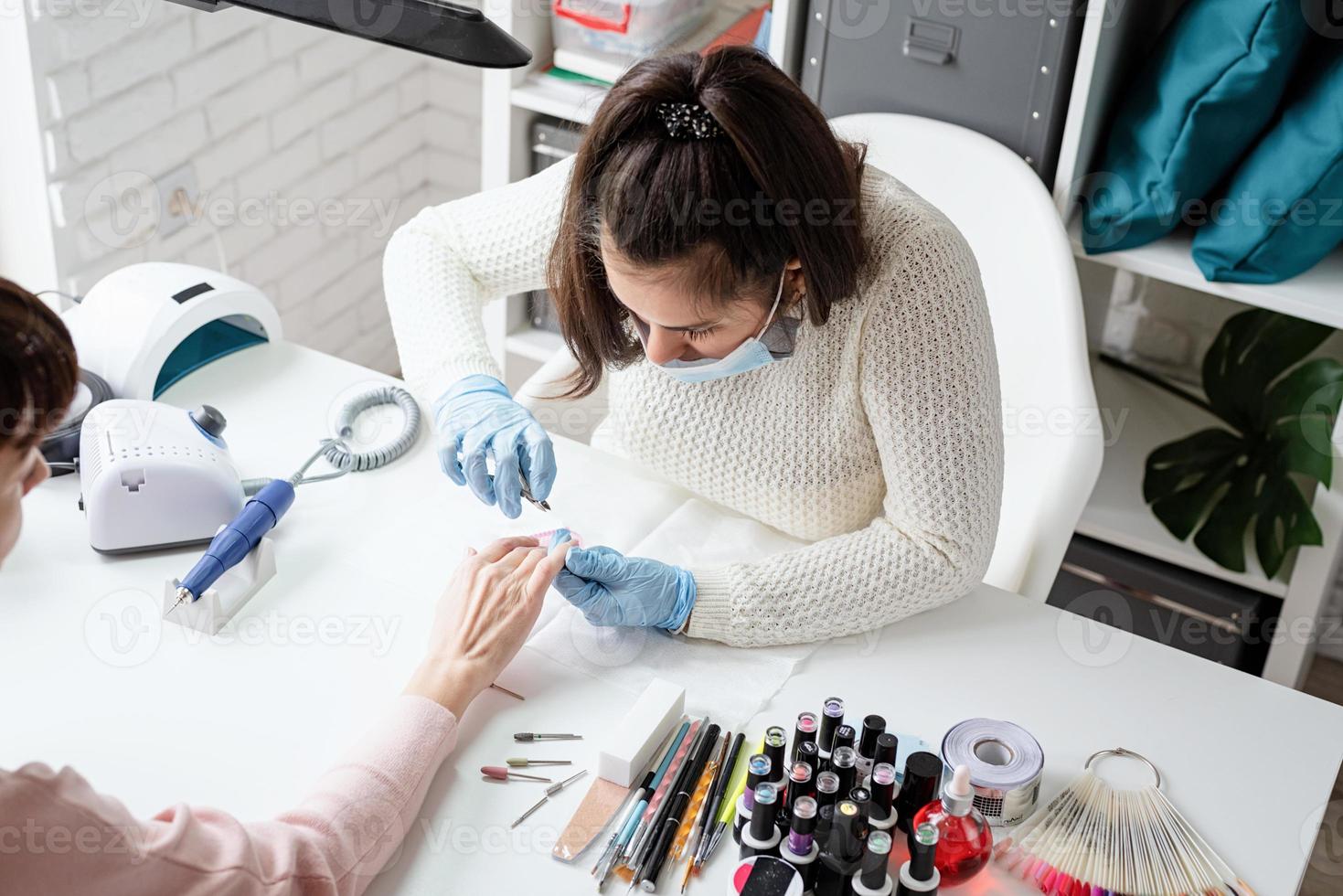 manicure-meester die een tang gebruikt om manicure voor een klant te maken foto