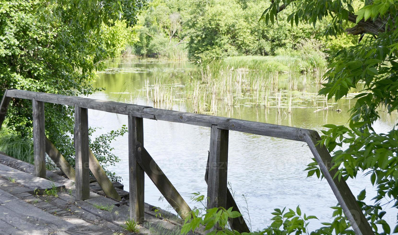 staande oude houten brug over rivier in gekleurde achtergrond foto