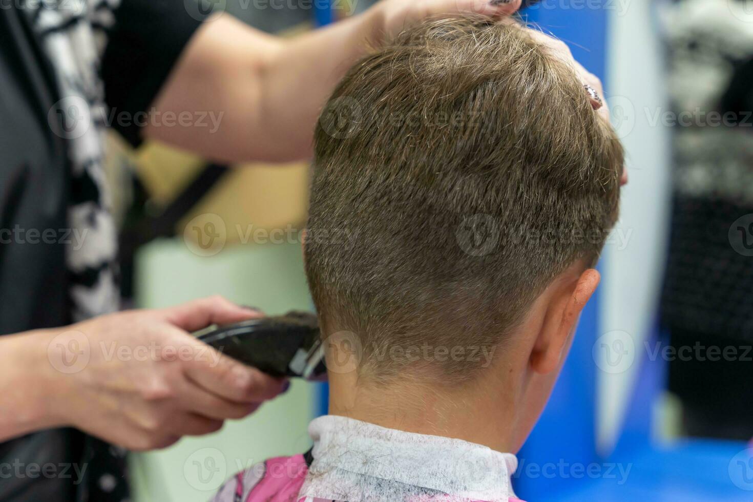 haar- snijdend voor een kind gebruik makend van een haar- tondeuse in een schoonheid salon foto