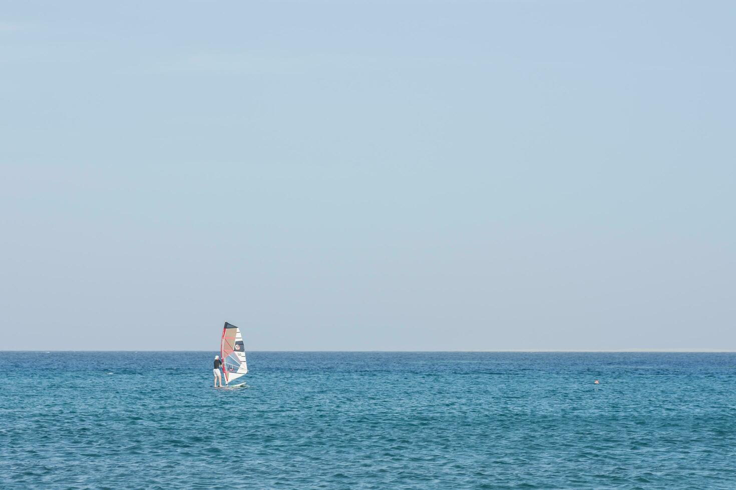 single windsurfer in blauw water en blauw lucht Aan vakantie foto