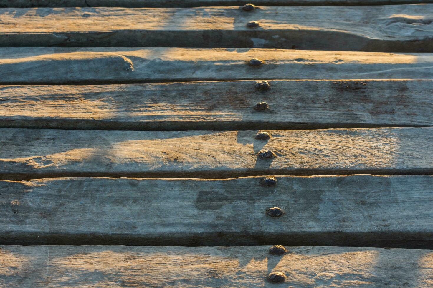 oud roestig ijzer klinknagels Aan een houten steiger in de zon gedurende zonsondergang foto