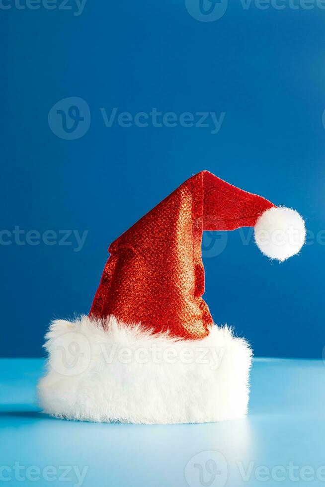 rood de kerstman claus hoed Aan blauw achtergrond. feestelijk Kerstmis of nieuw jaar concept. mockup foto