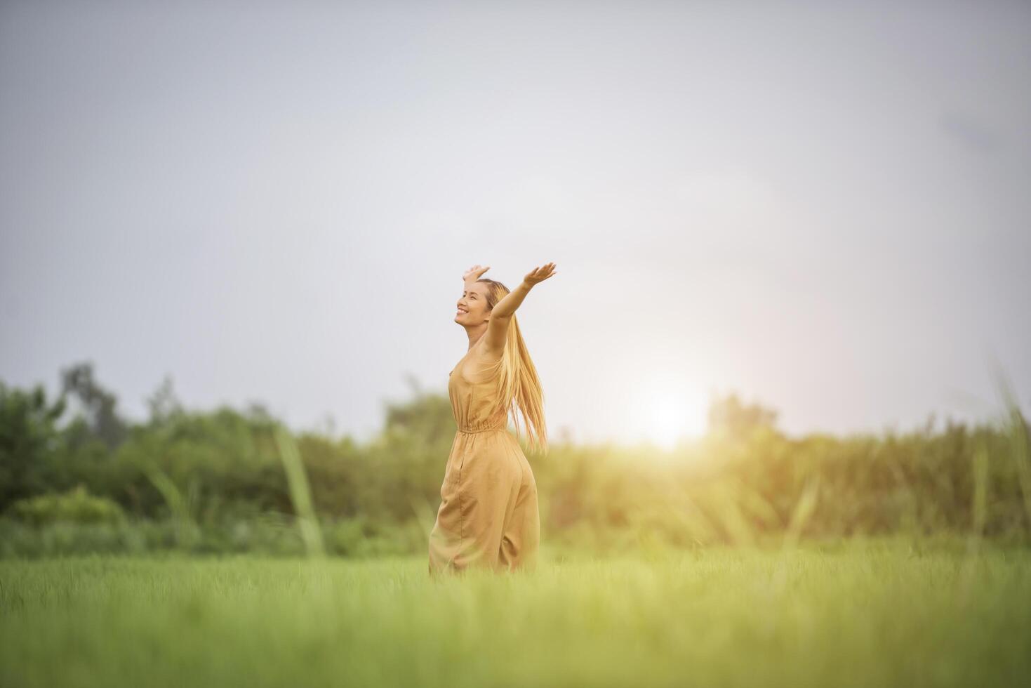 jonge vrouw die in grasveld staat en handen in de lucht steekt. foto