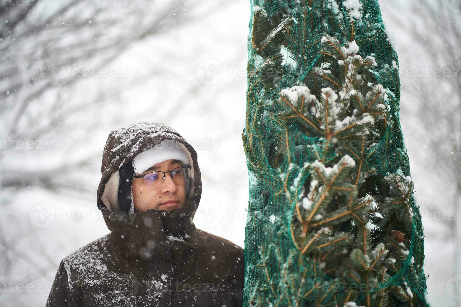 een Mens gebracht een Kerstmis boom in zijn werf gedurende een sneeuwstorm. foto