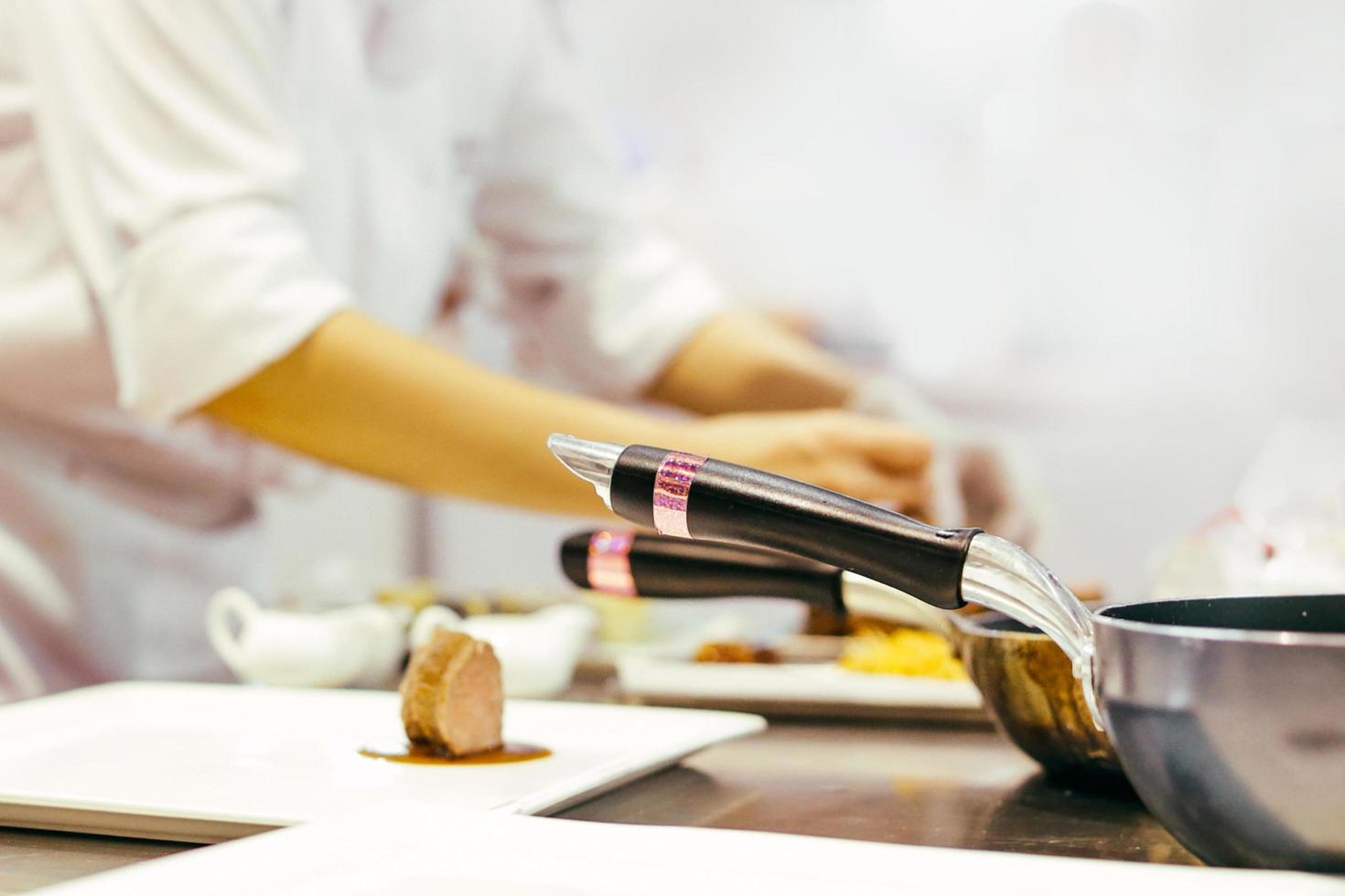 chef-kok koken, chef-kok die voedsel bereidt, chef-kok die schotel in de keuken decoreert foto