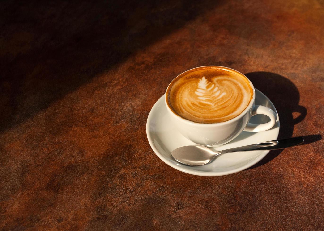 kopje hete latte art in middaglicht op houten tafel foto