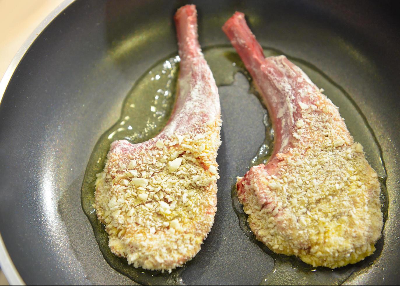 chef-kok bereidt voedsel, maaltijd, in de keuken lamsrack frituren op pan foto