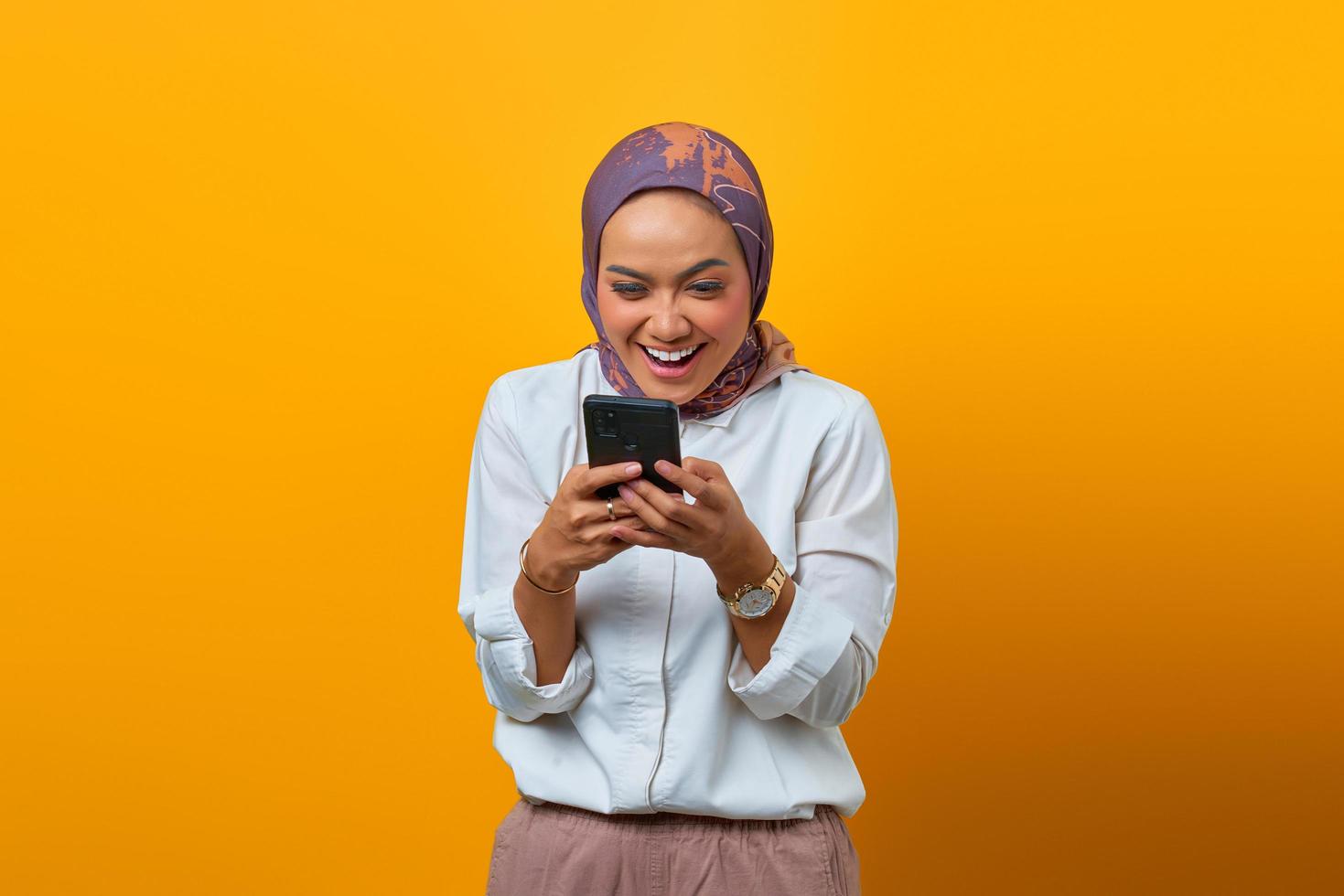 vrolijke aziatische vrouw die naar smartphone kijkt en goed nieuws krijgt foto