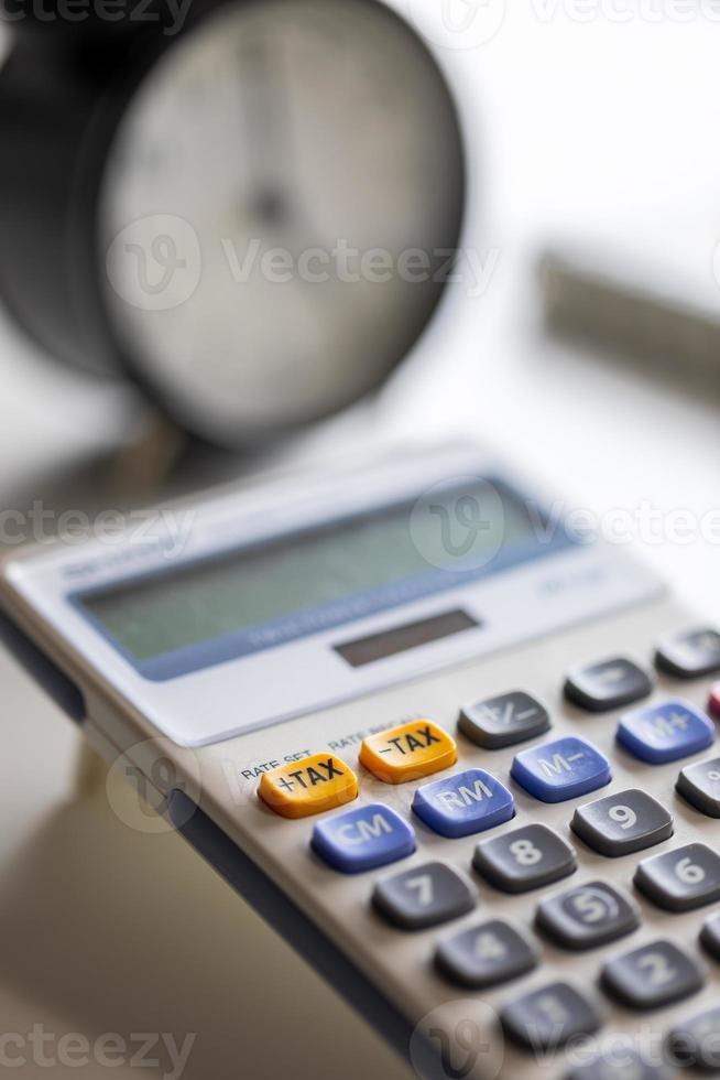 selectieve focus op plus belastingknop van rekenmachine met wazige klok. foto