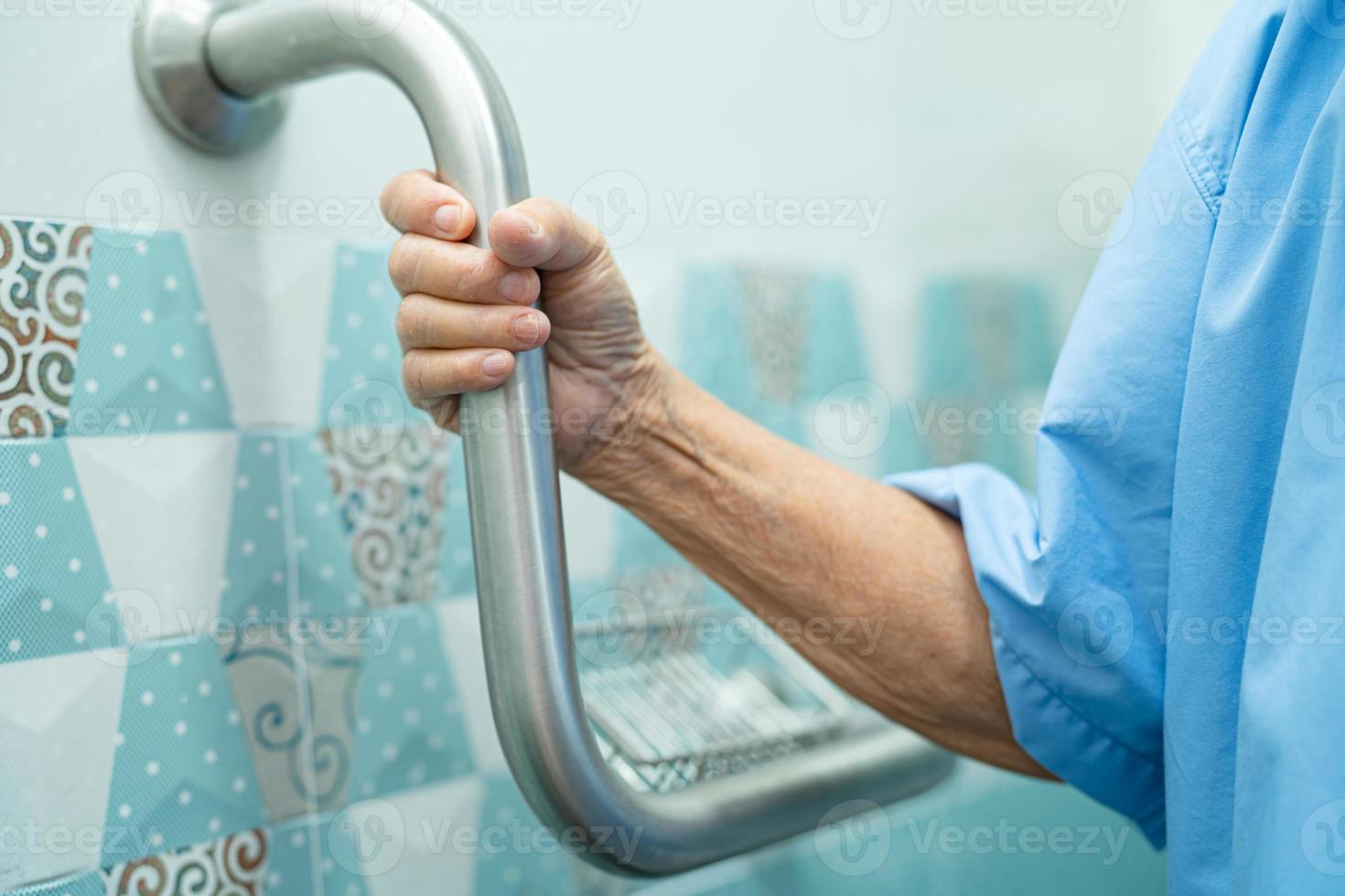 Aziatische senior vrouw patiënt gebruik handvat beveiliging in toilet foto