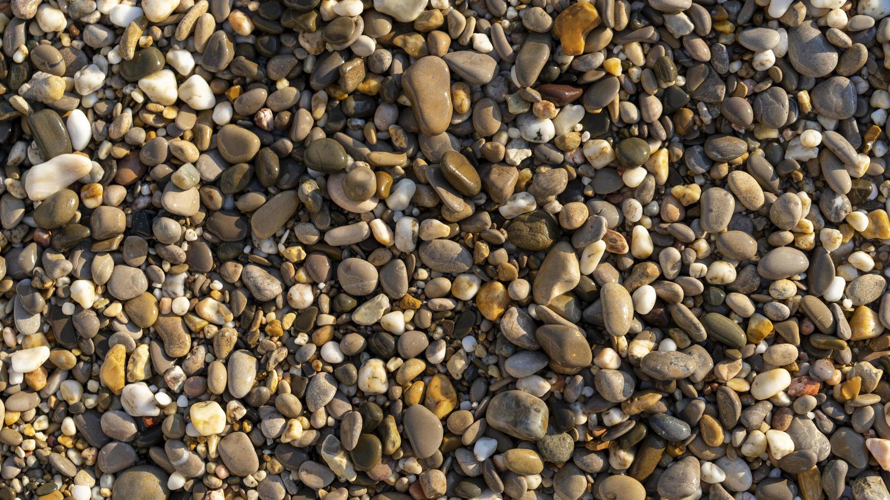 natuurlijke achtergrond met kleine zeekiezelstenen op het strand foto