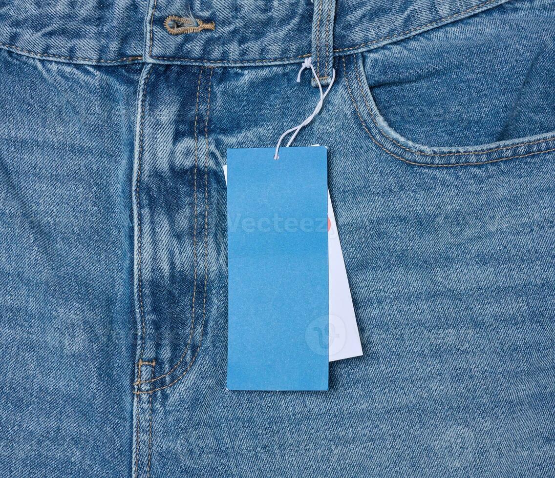papier prijs label Aan een touw gebonden naar de tailleband van blauw jeans foto