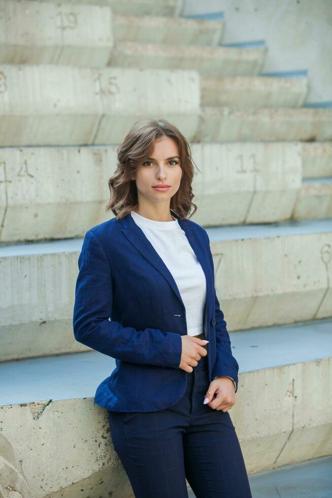 portret van een geslaagd bedrijf vrouw in voorkant van modern bedrijf gebouw. jong manager poses buiten. vrouw werknemer van een kantoor. foto