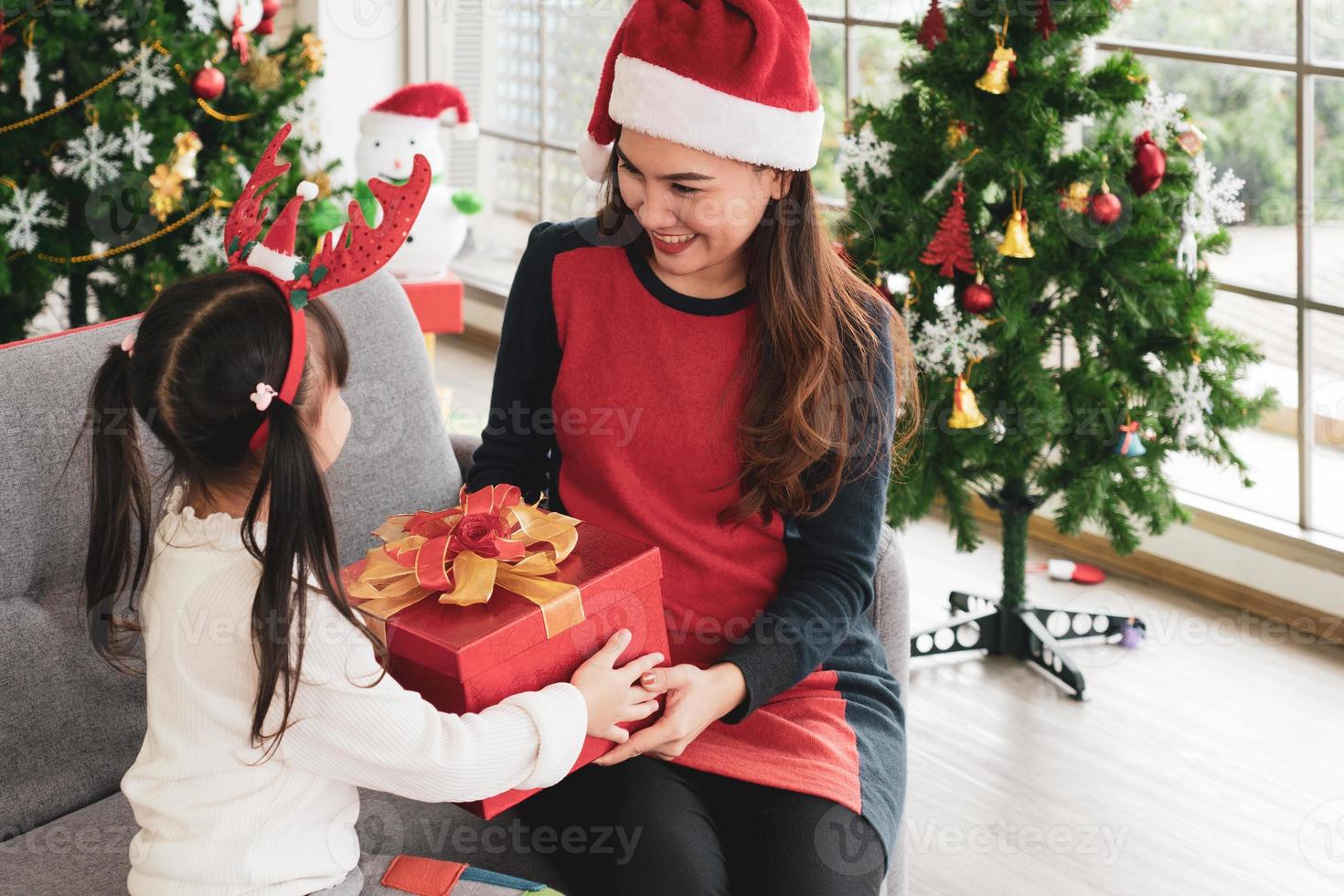 Aziatische moeder en kind openen de doos met kerstcadeaus samen foto