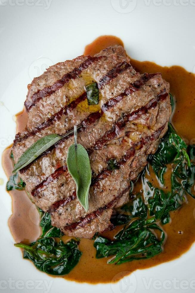 rundvlees steak met jus en kruiden Aan een wit bord top visie foto