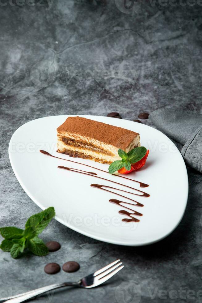 spons taart gevulde met aardbeien, munt en chocola siroop Aan een wit bord kant visie foto