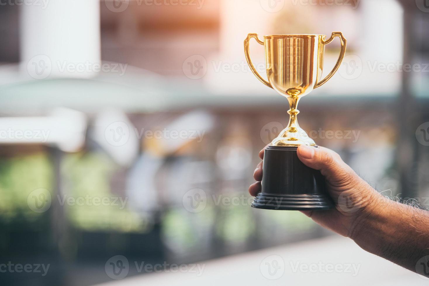 kampioen gouden trofee voor winnaar in hand achtergrond foto