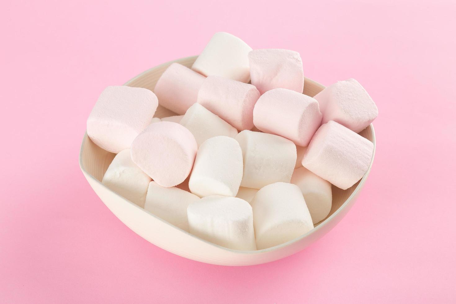 marshmallow in kom op pastelroze achtergrond foto