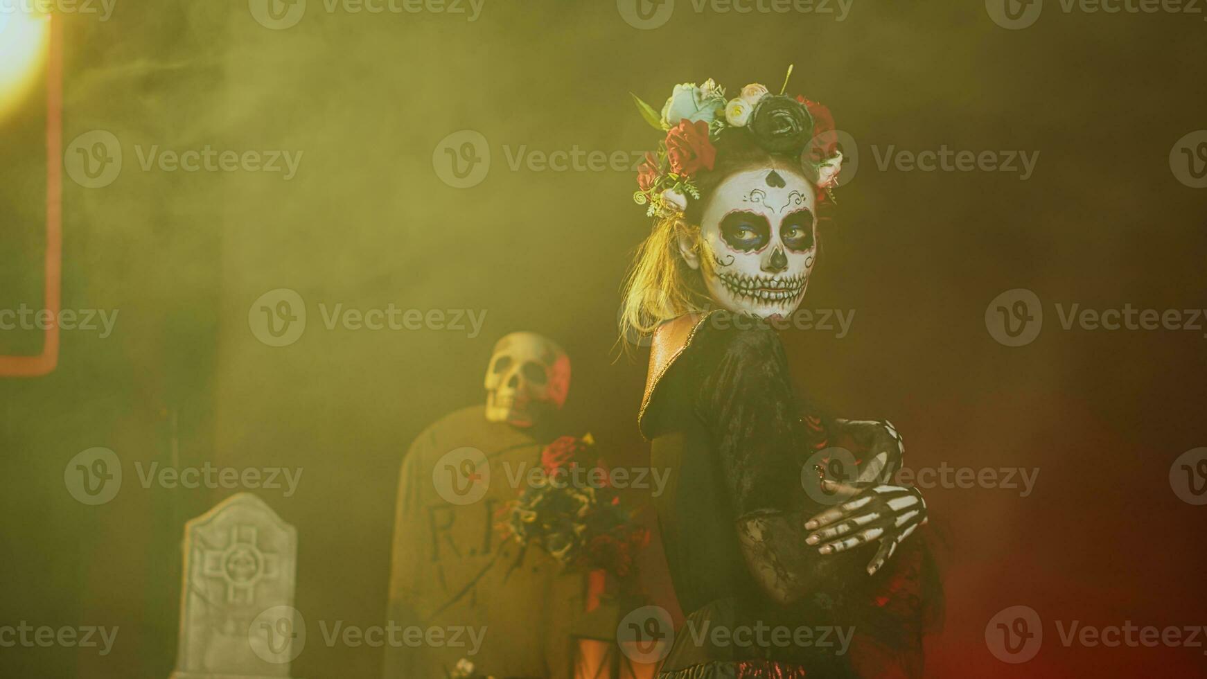 glamoureus vrouw met suiker schedel maken omhoog en bloemen hoofdband, gekleed in godin van dood kostuum net zo de kerstman muerte. dios de los Muertos kunst naar vieren Mexicaans traditie in studio. handheld schot. foto