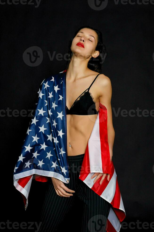 portret vrouw atleet verpakt in Amerikaans vlag tegen zwart achtergrond foto