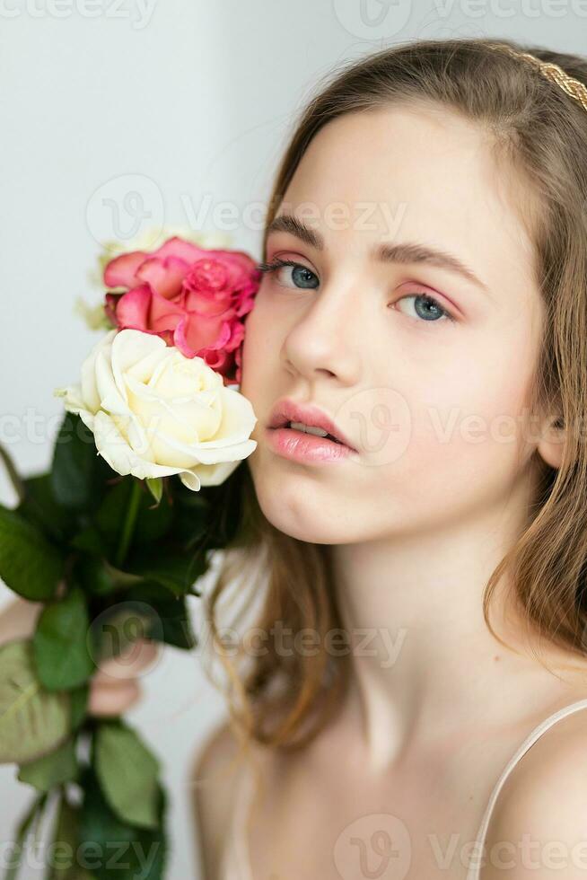 weinig mooi meisje in roze houdt de boeket van rozen. foto