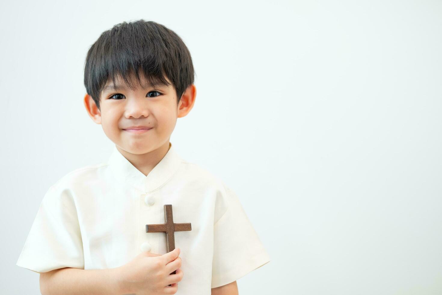 weinig Aziatisch jongen bidden met Holding de kruis, christen concept foto