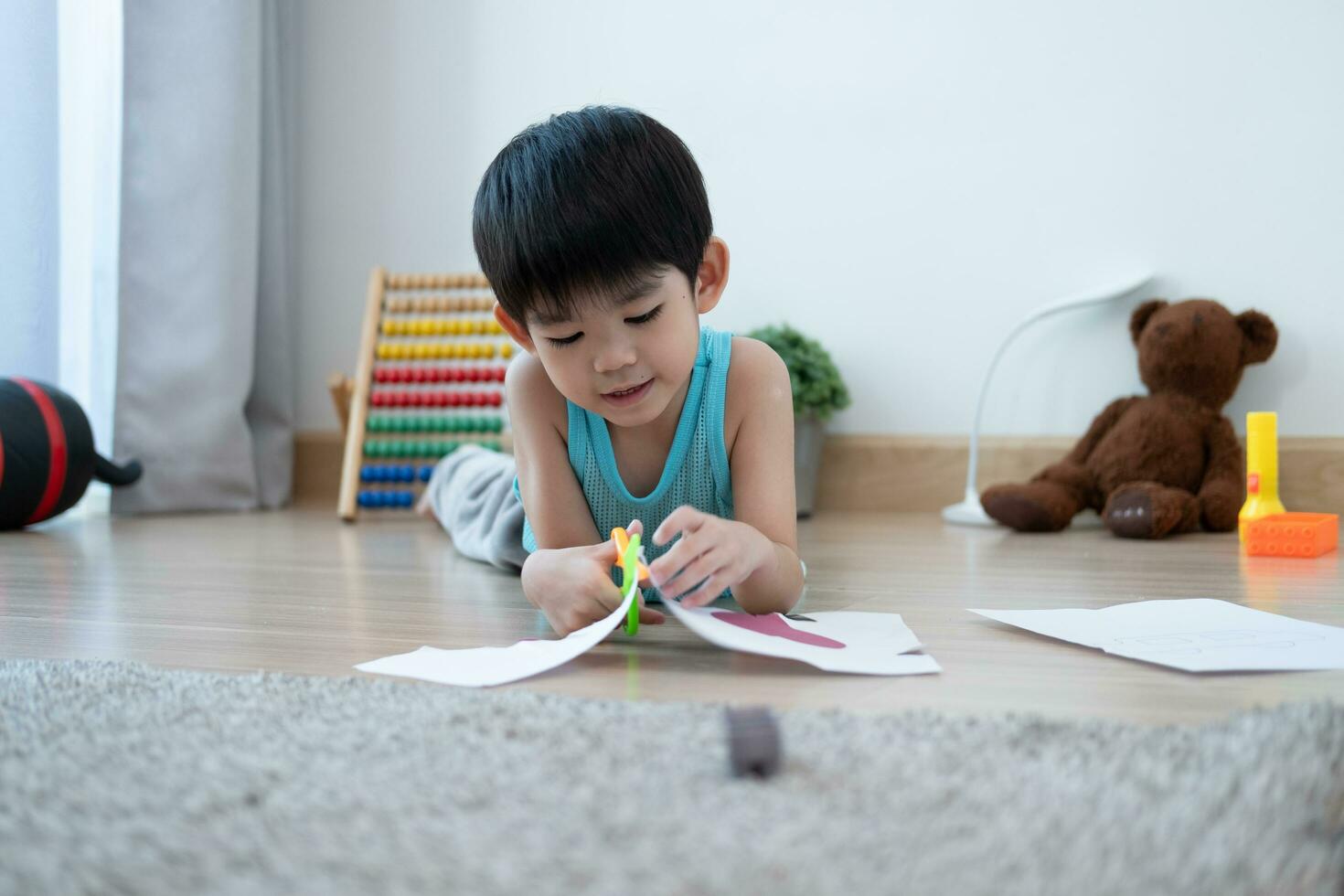Aziatisch jongen gebruik makend van schaar naar besnoeiing papier langs lijnen aan het leren buiten de klas foto
