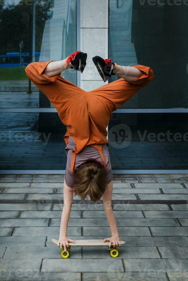 parkour truc Aan skateboard. tiener meisje staat Aan haar handen Aan skateboard. foto