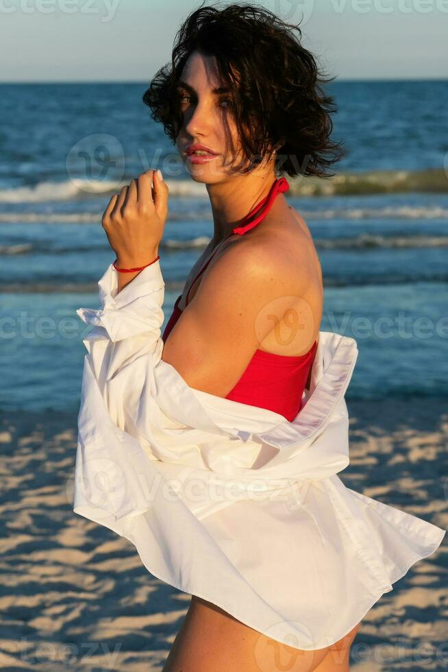 sexy terug van een mooi vrouw in rood bikini Aan zee achtergrond foto