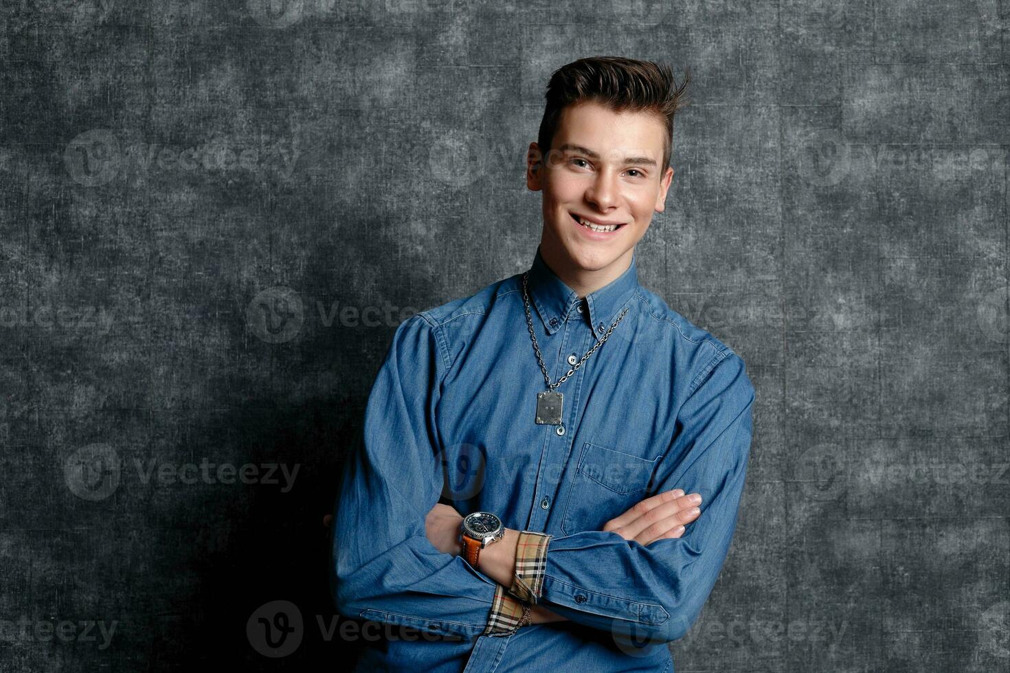 Mens in denim shirt, armen Aan heupen, grijs achtergrond. foto