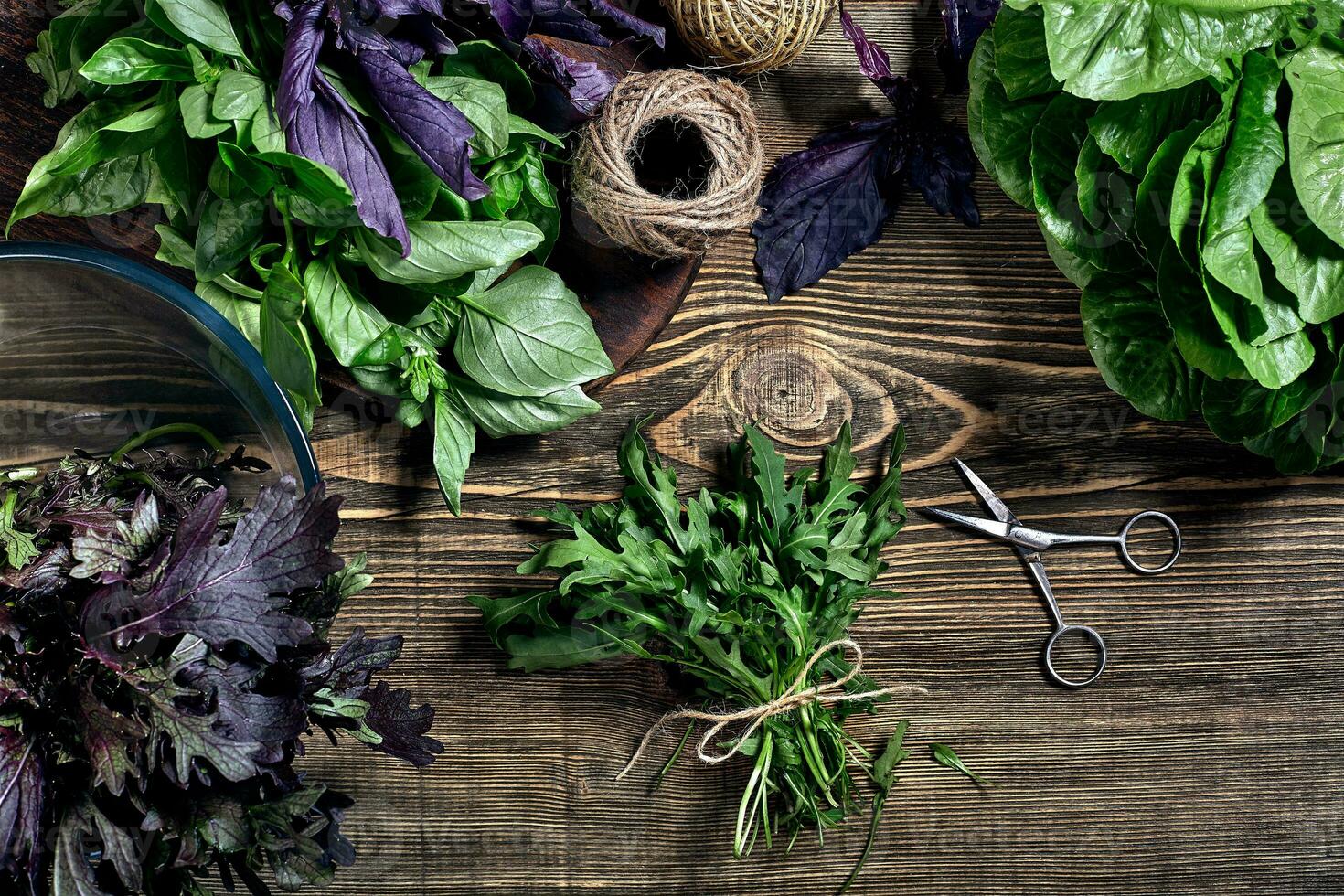 verscheidenheid van vers biologisch kruiden Aan houten achtergrond. vers geoogst kruiden inclusief basilicum, rucola. top visie. kopiëren ruimte. foto