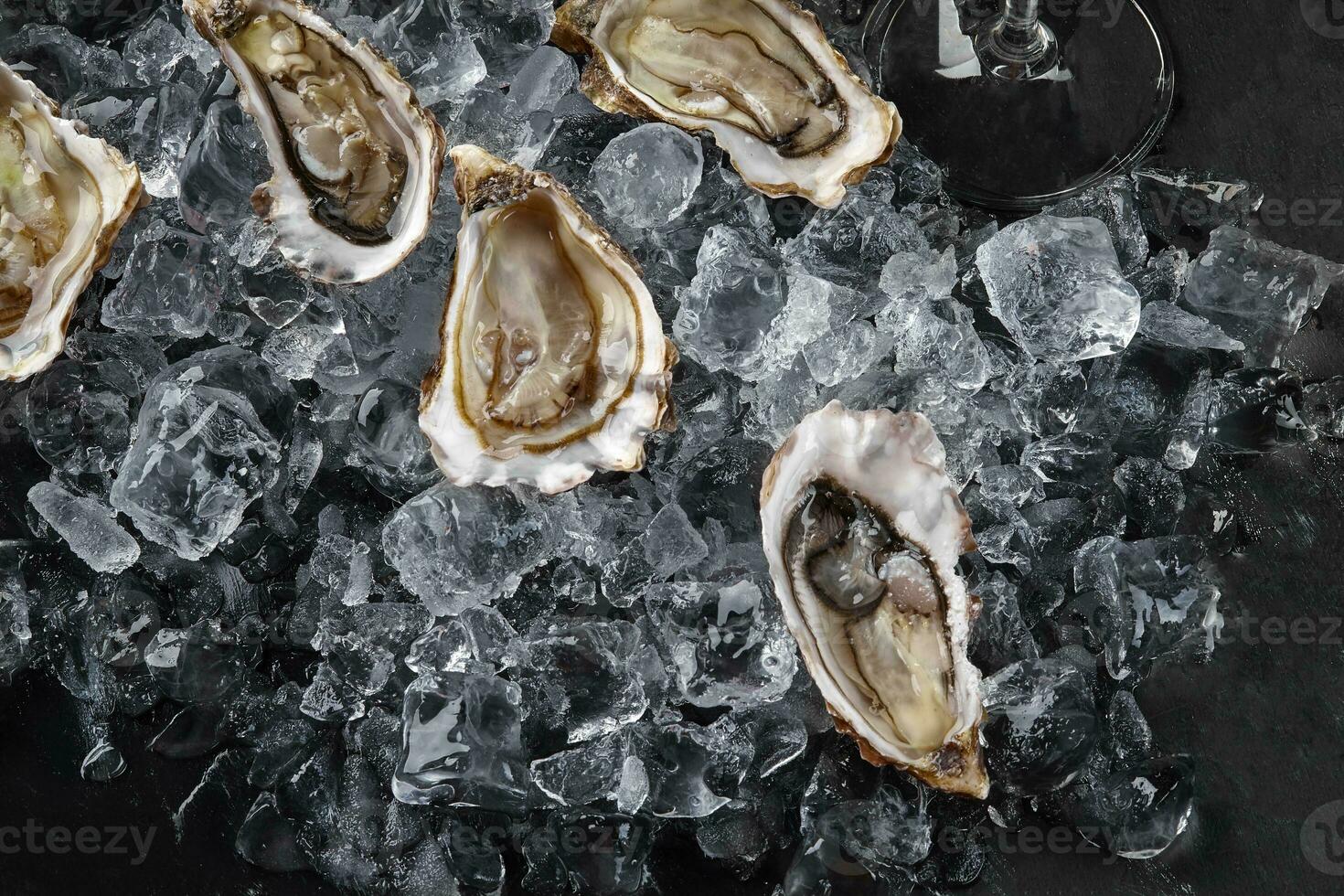 vers geopend oesters in ijs Aan een zwart steen getextureerde achtergrond. top visie. detailopname schot. foto