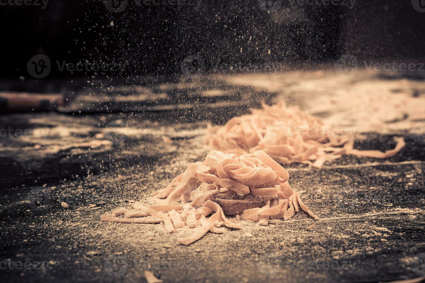 huis vers rauw pasta Aan de keuken tafel zwart concreet, bestrooi met meel. foto