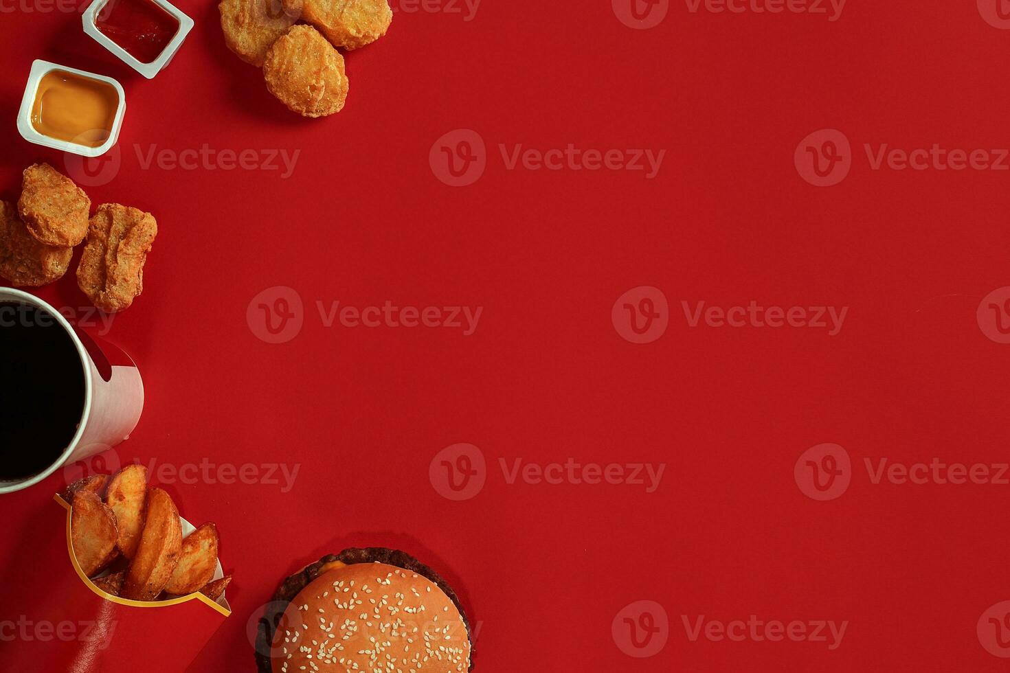 concept van bespotten omhoog hamburger, aardappelen, saus, kip klompjes en drinken Aan rood achtergrond. kopiëren ruimte voor tekst en logo. foto