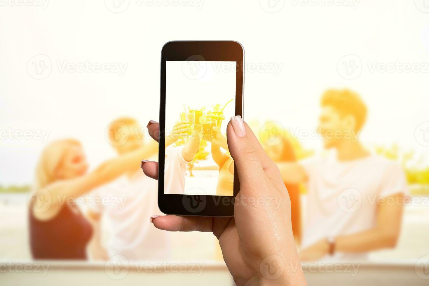 nauw beeld van vrouw handen Holding mobiel telefoon met foto camera mode Aan de scherm. groep van gelukkig vrienden drinken cocktails Bij zomer bar