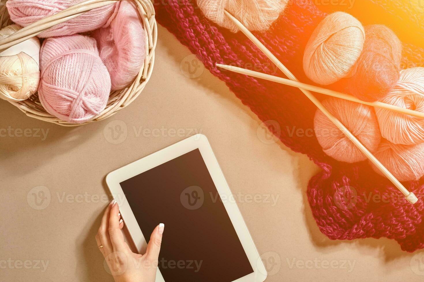 roze en Purper ballen van wol draden met breiwerk naalden aan het liegen in mand Aan beige achtergrond. bespotten omhoog achtergrond voor uw ambacht breien. zon gloed foto