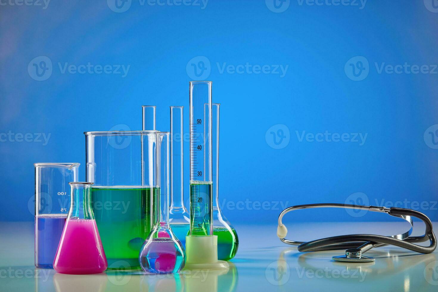 kleurrijk chemisch reagentia in bekers, medisch kolven, meten cilinder en phonendoscope, blauw achtergrond. coronavirus, wereldwijd pandemisch covid-19 foto