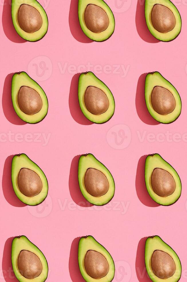 kleurrijk fruit patroon van vers gesneden avocado helften met kuilen Aan koraal roze achtergrond, top visie foto