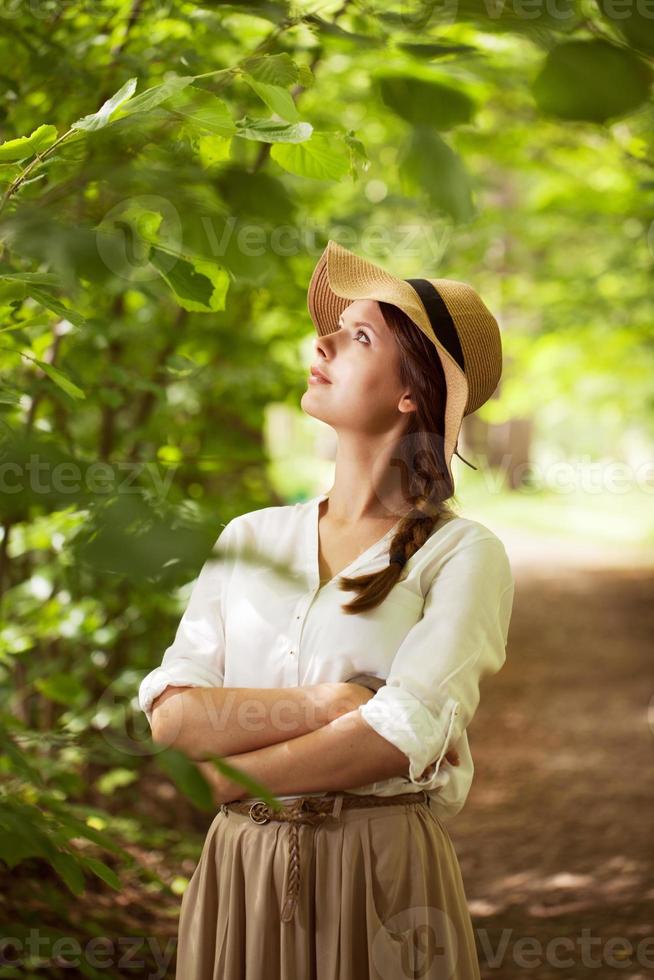 mooie vrouw in een hoed tussen groen gebladerte foto