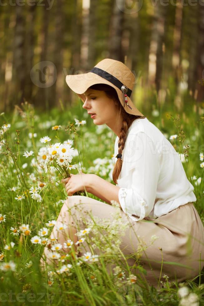 leuke vrouw plukt madeliefjes op een weide foto