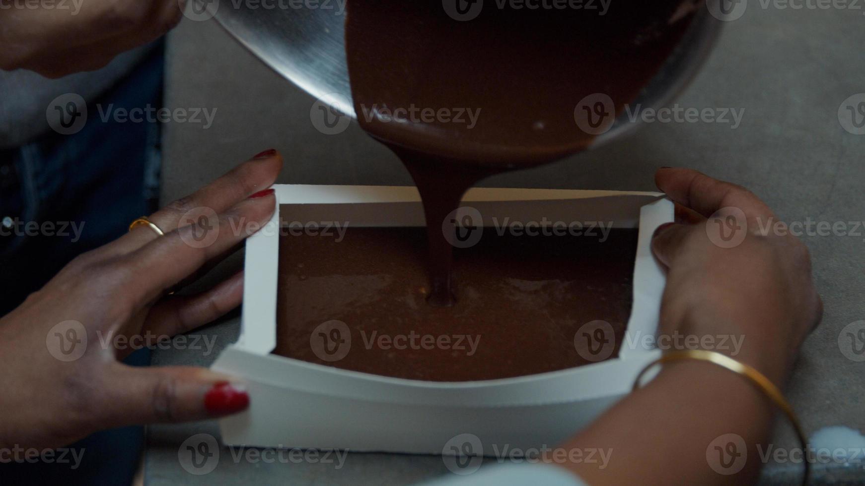 zwarte persoon giet cakemix in papieren cakevorm foto