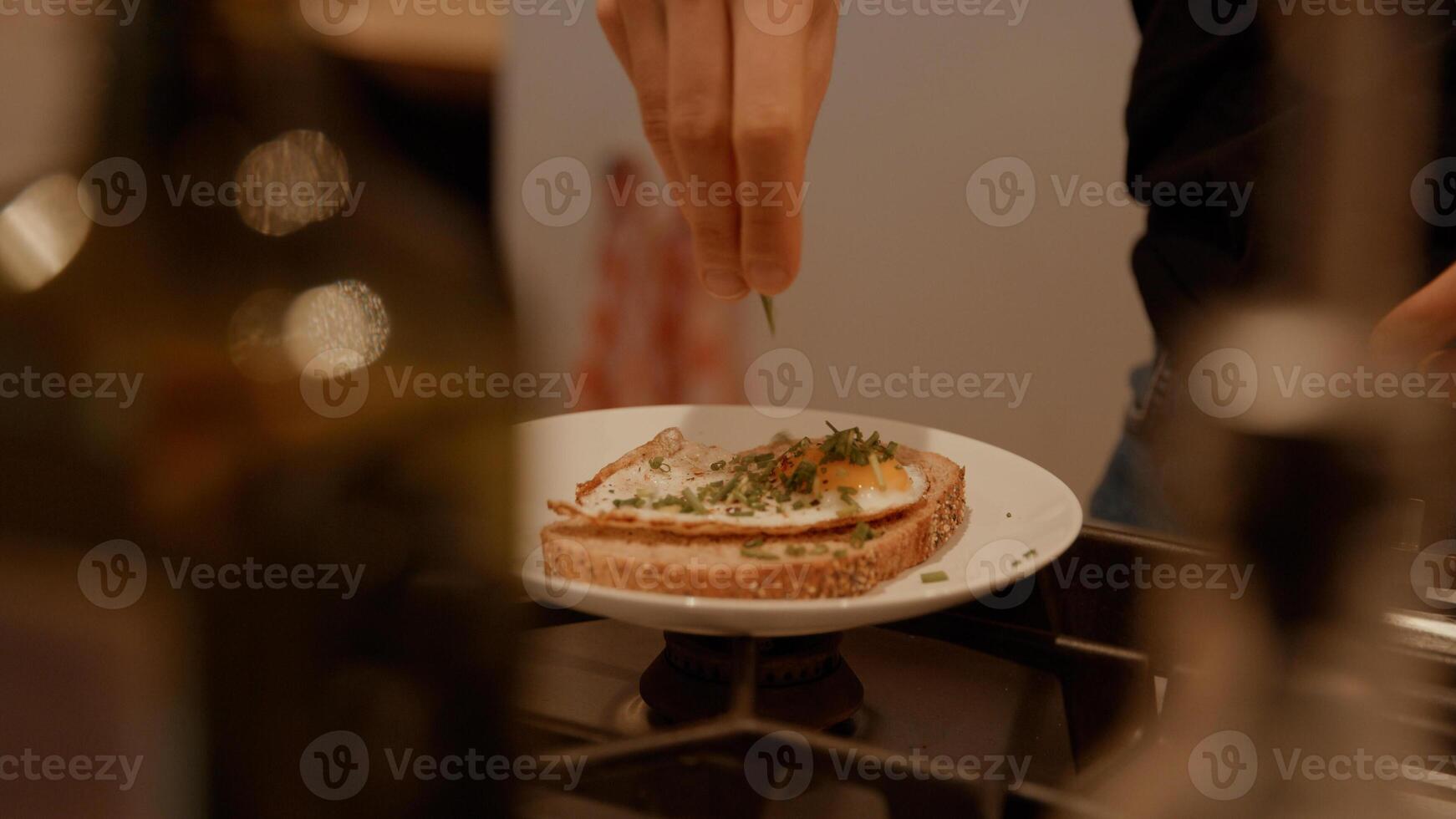 handen van vrouw schikken gebakken ei en bieslook op sandwich foto