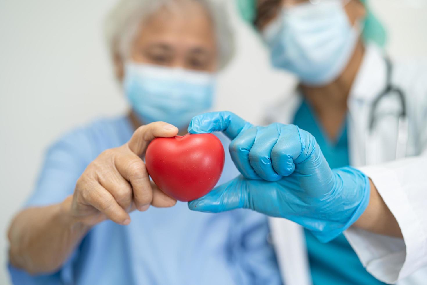 arts die pbm met masker draagt, geeft een rood hart om het coronavirus te beschermen foto