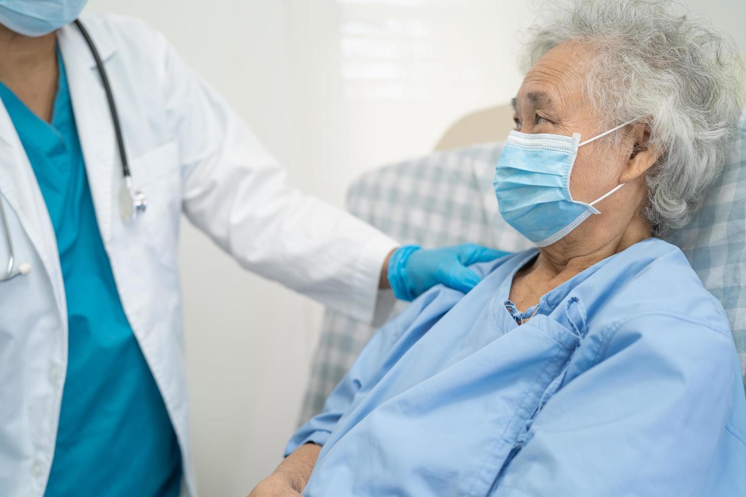 arts helpt aziatische senior patiënt die een masker draagt om het coronavirus te beschermen foto