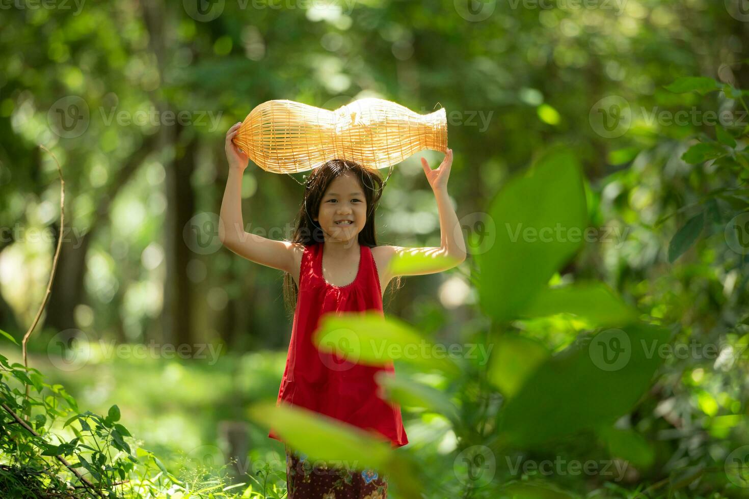 weinig Aziatisch meisje in rood jurk Holding visvangst uitrusting in de Woud, landelijk Thailand leven leven concept foto