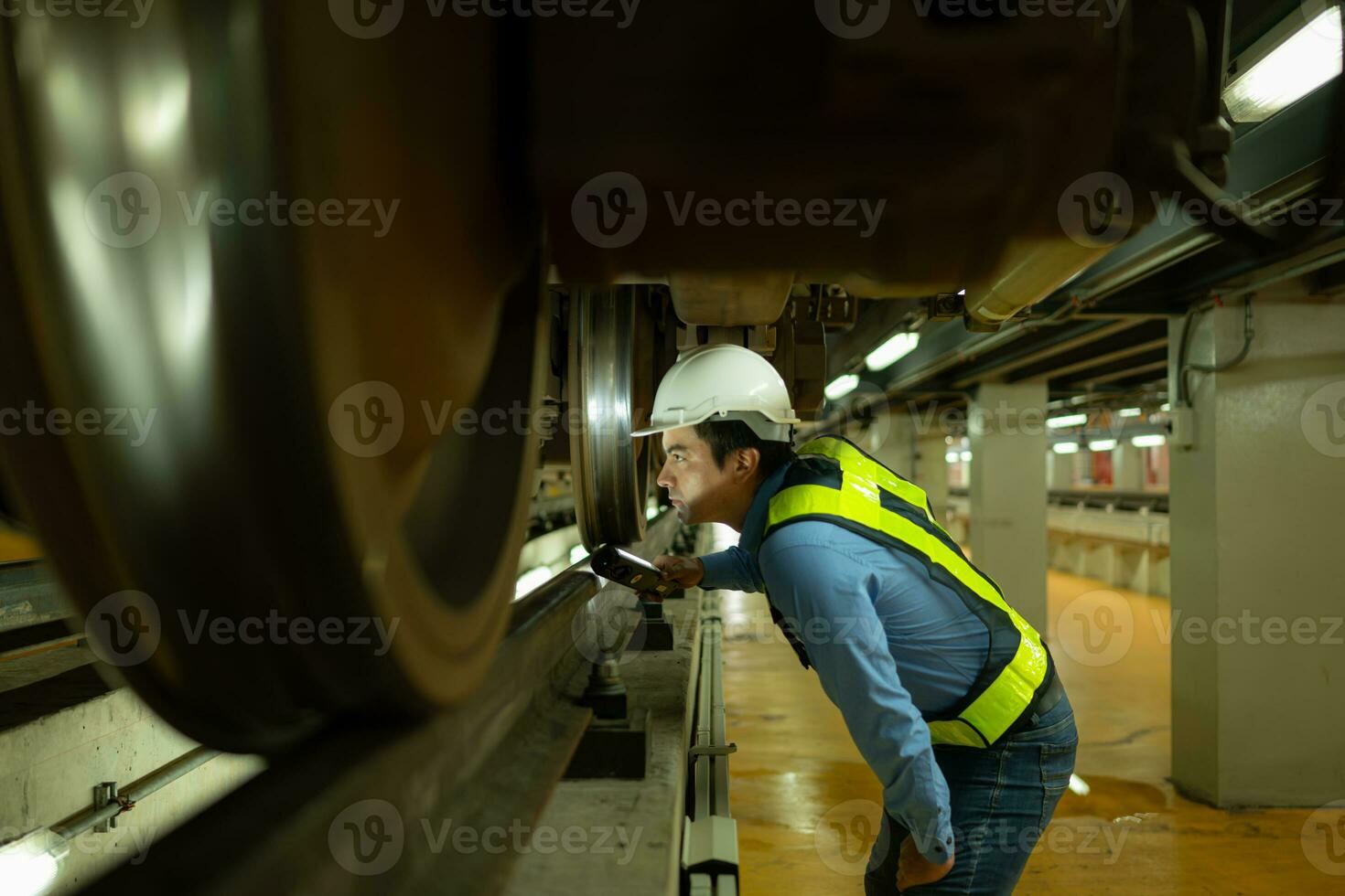 ingenieurs voor elektrisch treinen na detecteren moeilijkheden met de elektrisch trein machinerie gebruik zoeklichten naar bevind zich en controleren beschadigd secties. in de elektrisch trein reparatie winkel foto