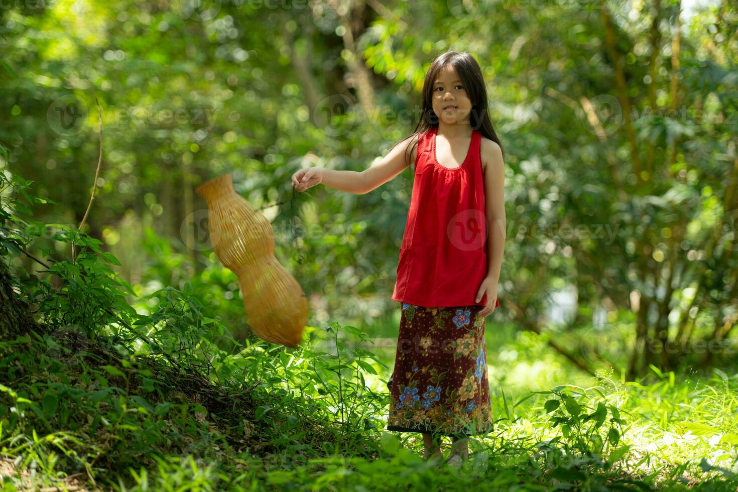 weinig Aziatisch meisje in rood jurk Holding visvangst uitrusting in de Woud, landelijk Thailand leven leven concept foto